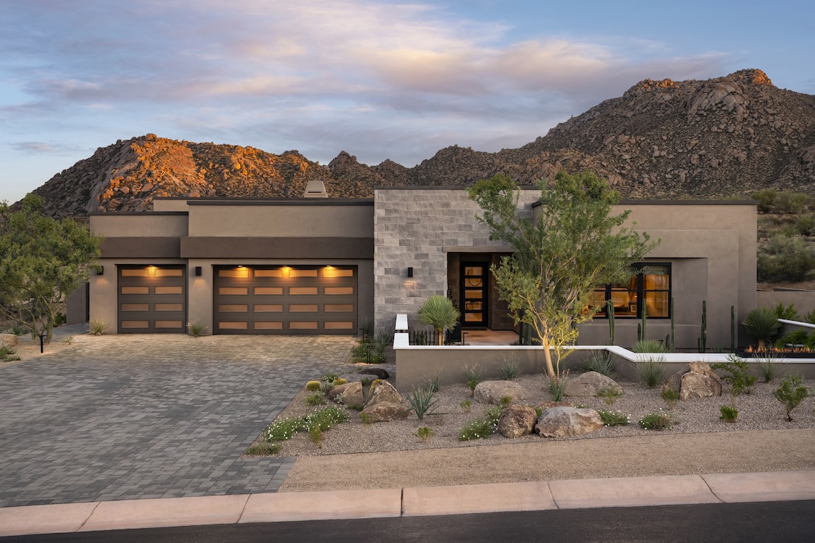 Contemporary desert home exterior with modern architecture, natural landscaping, and a dramatic mountain backdrop.