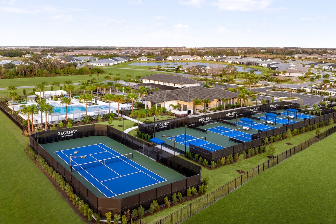 Aerial view of a Toll Brothers Regency clubhouse with resort-style pool, tennis court, and multiple pickleball courts.