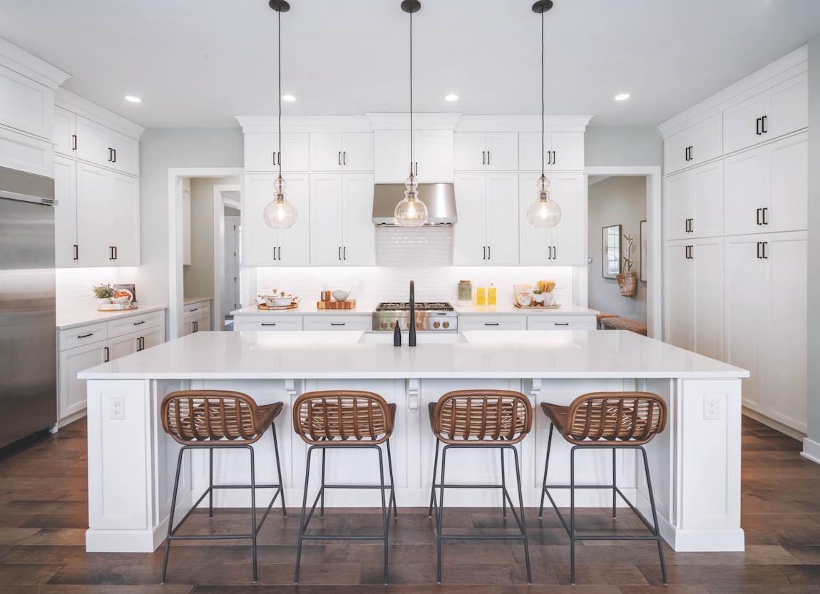 White kitchen with wicker island chairs.