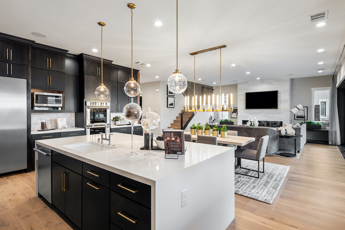 Kitchen with waterfall countertop island and black and white color scheme.