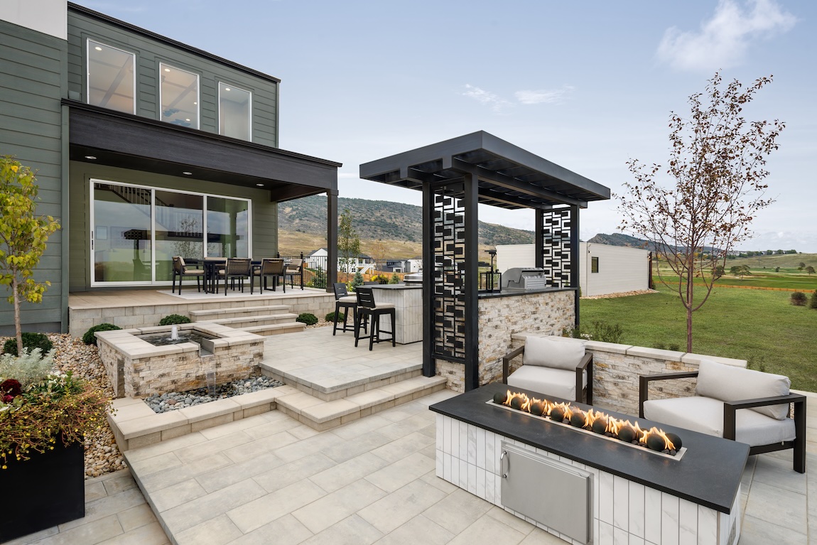 Transitional outdoor design with fire feature, built-in grill, pergola, and tiered patio.