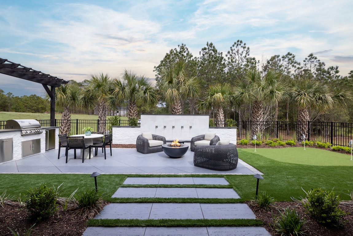 Modern outdoor design with fire pit, grilling station, dining area, and putting green.