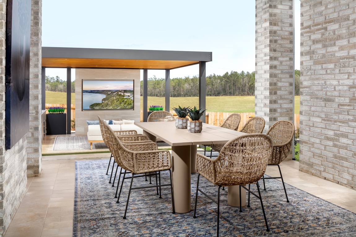 Classical outdoor dining space with woven seating and adjacent lounge area overlooking the landscape.