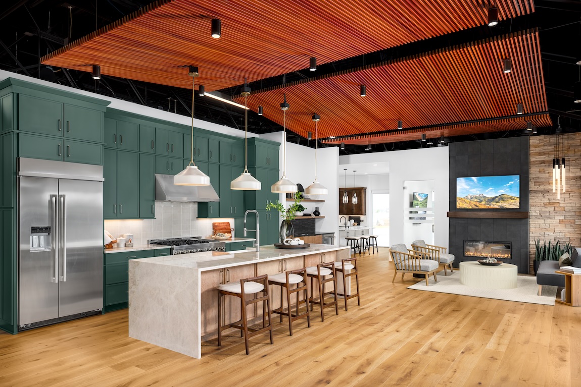 Kitchen display inside the Denver Toll Brothers Design Studio featuring green cabinetry, waterfall island, and modern statement lighting.