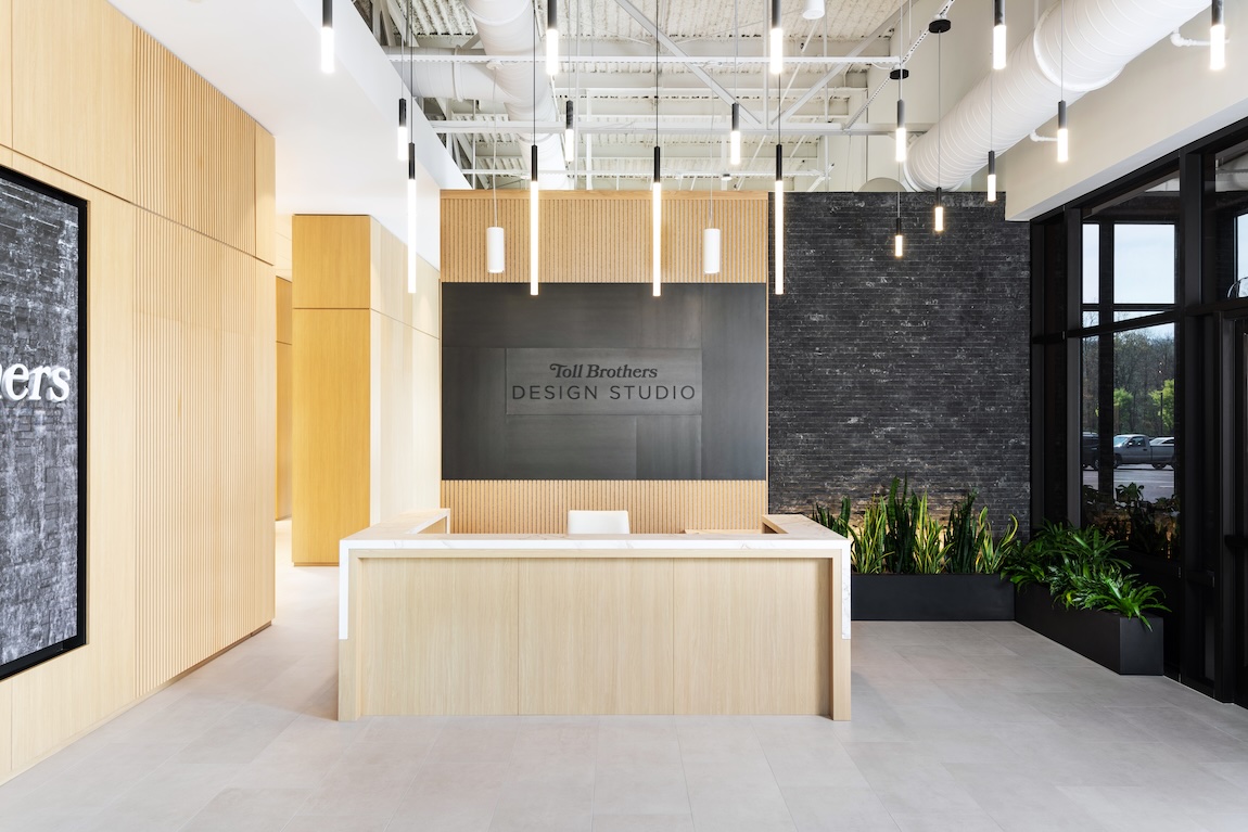 Stylish reception area with pendant lighting, light wood accent walls, and walkway to main design studio spaces.