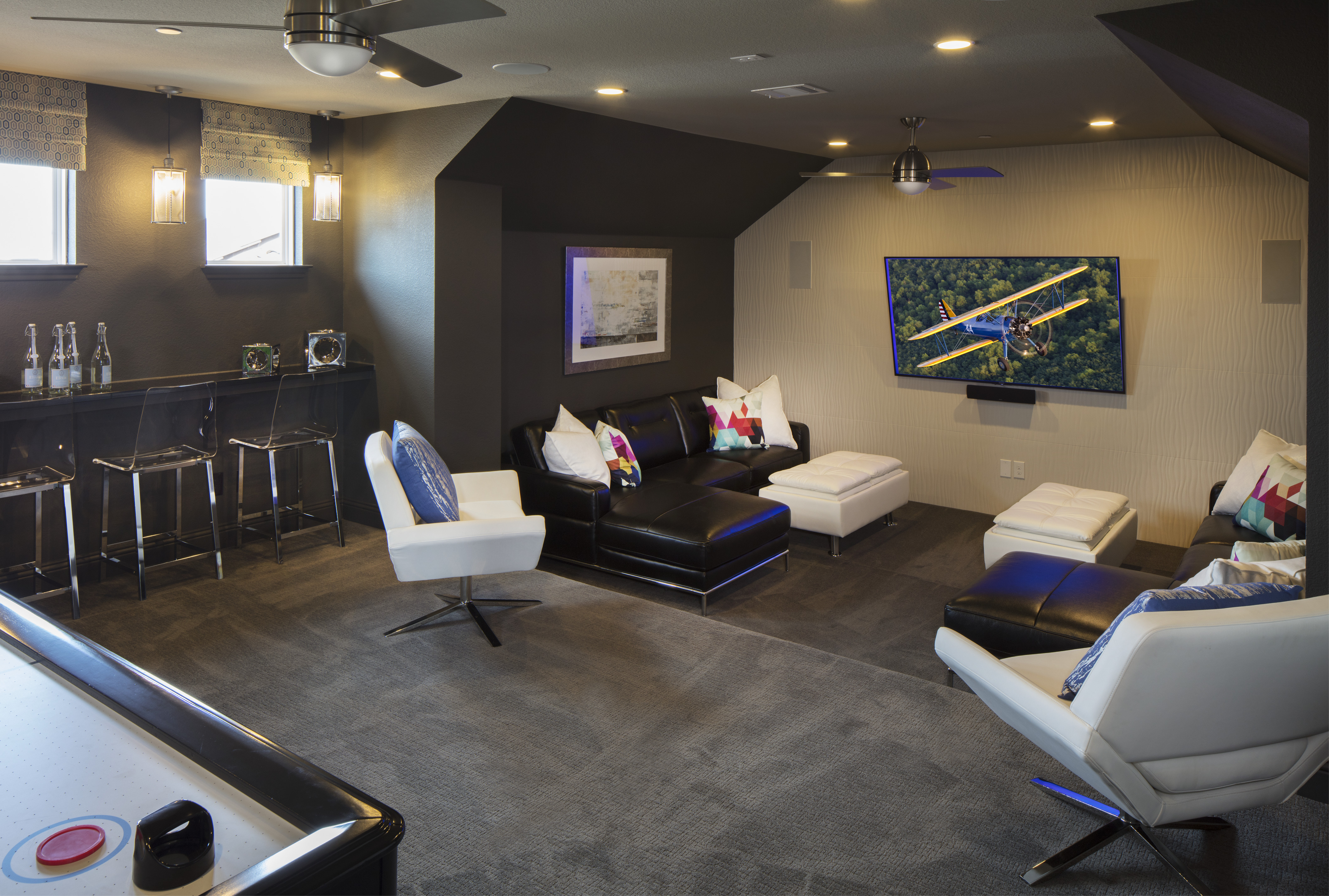 Basement game room with seats in front of a tv.