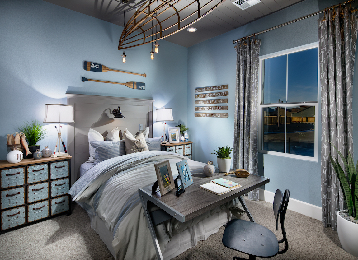 Light blue teen bedroom featuring fishing theme and workplace at foot of the bed