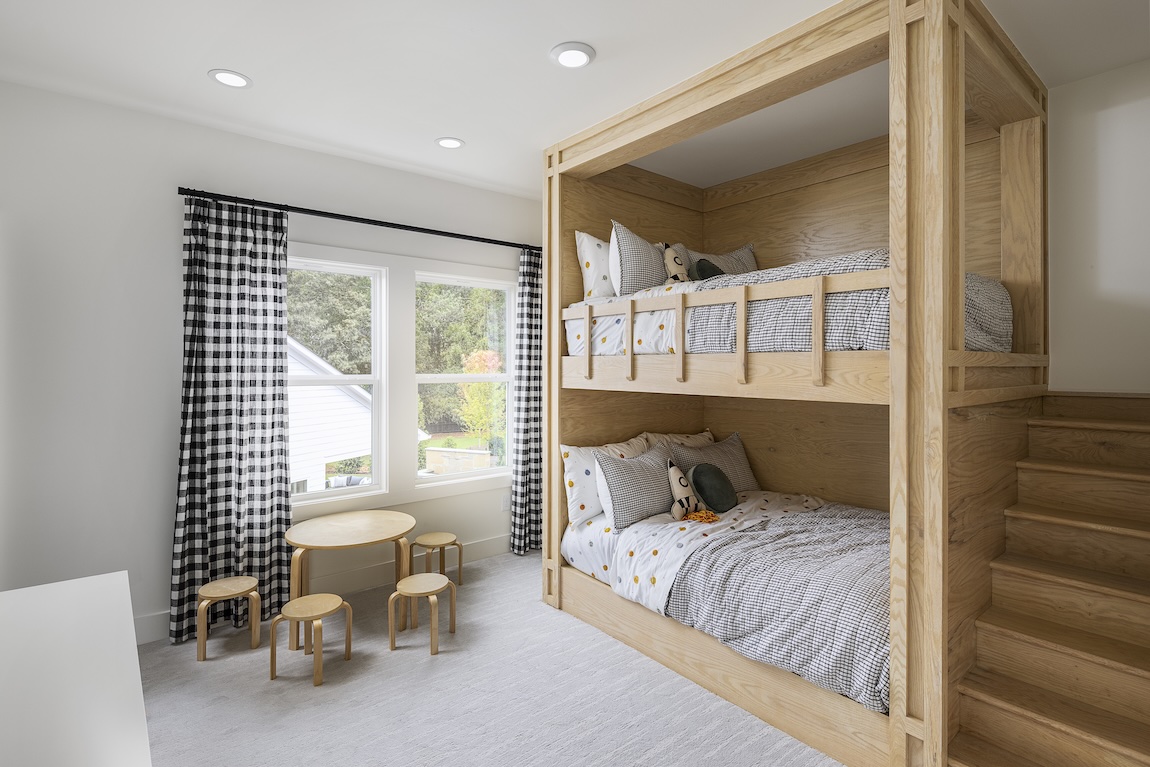 shared bedroom with wooden bunk beds and a craft table.