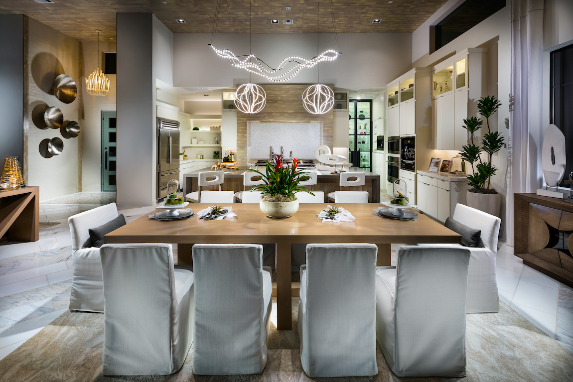 Covered dining chairs with silver light fixtures and wooden table in kitchen