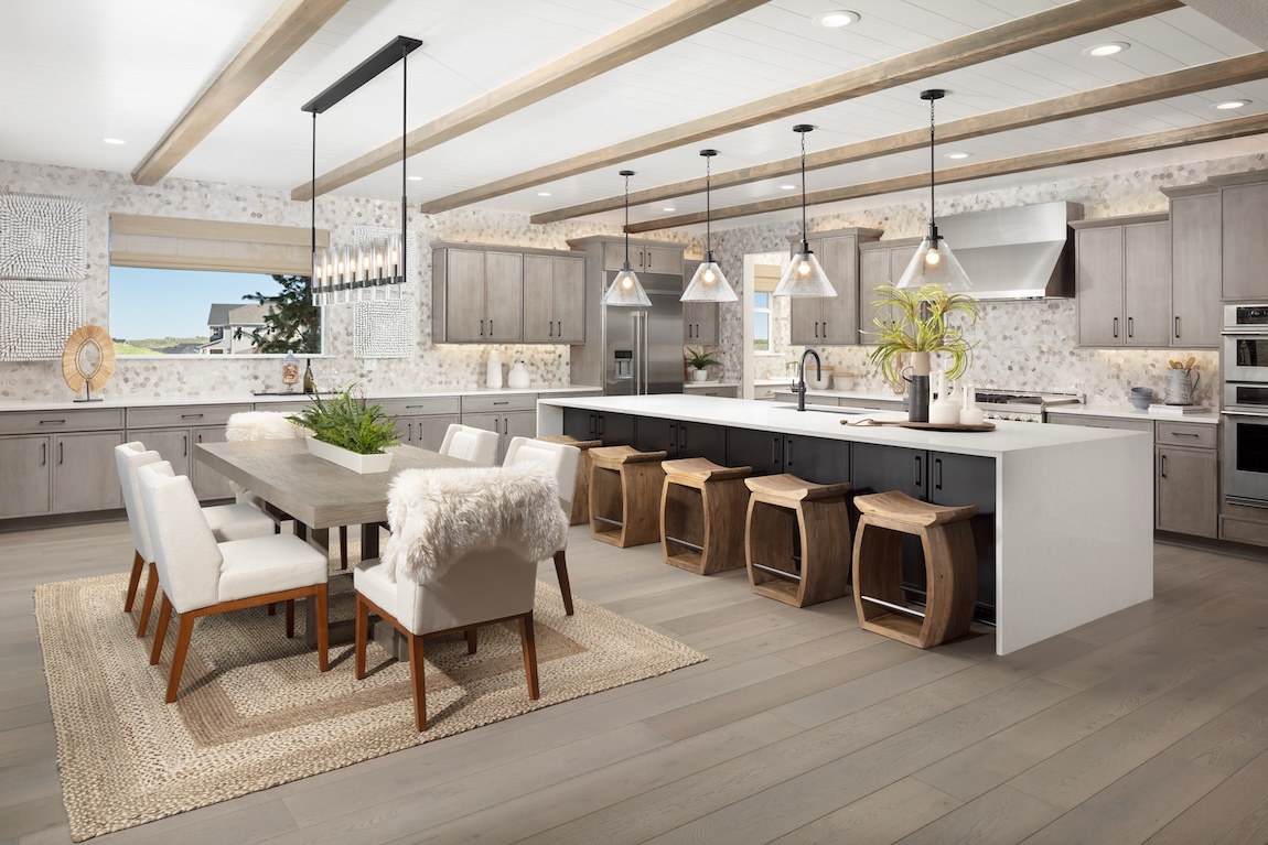 Casual dining area beside a spacious kitchen featuring exposed wood ceiling beams, neutral finishes, and a large center island.