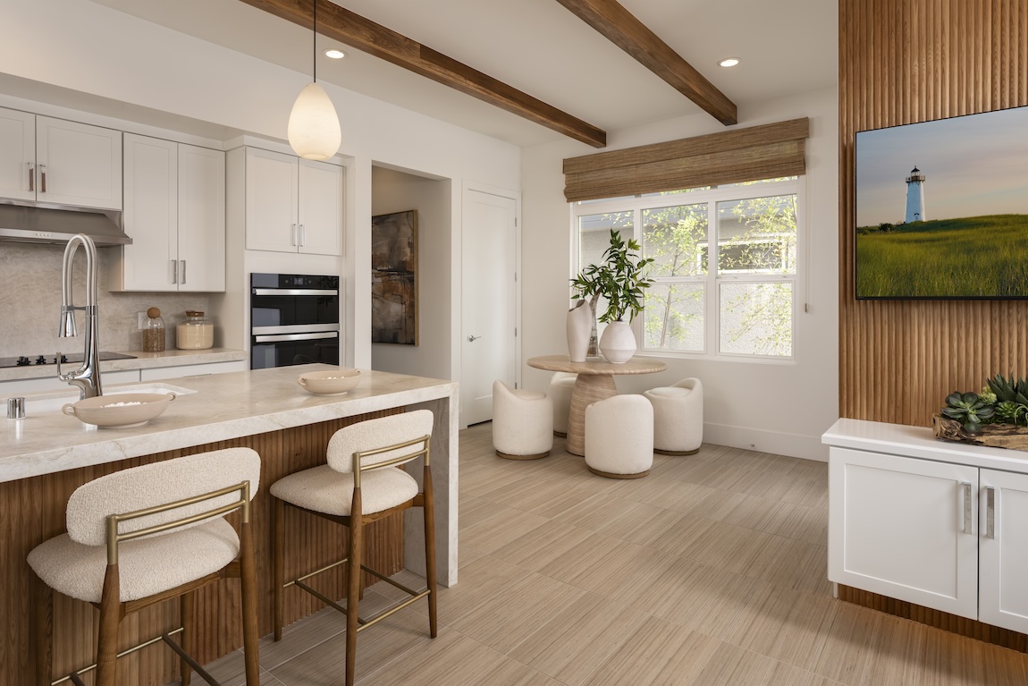 Cozy kitchen dining nook with a round pedestal table, upholstered stools, wood accents, and a nearby center island.