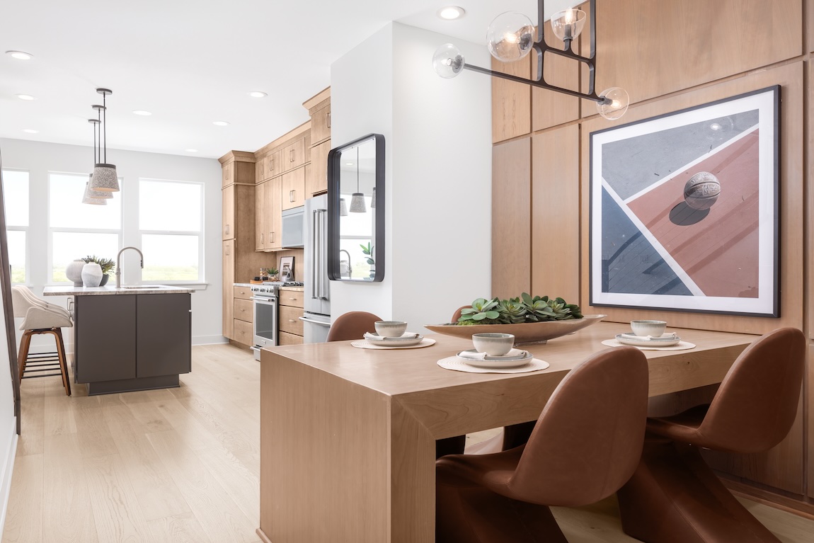 Modern breakfast nook with a built-in wood dining table, warm leather chairs, and contemporary statement lighting.