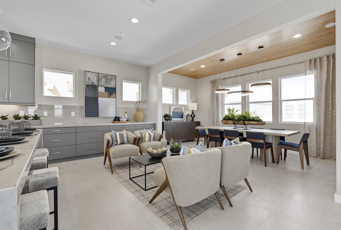 Open-concept casual dining area with a rectangular table, modern pendant lighting, and an adjacent lounge space.
