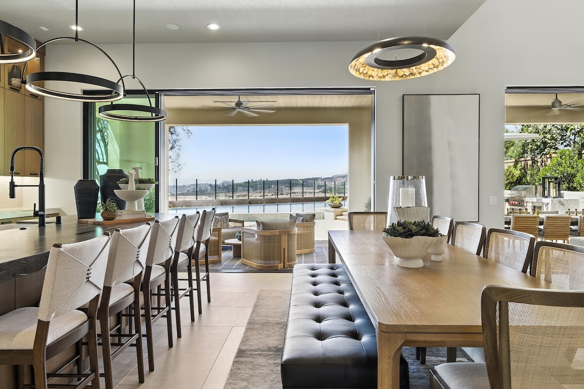Breakfast nook with a wood dining table, upholstered bench seating, and large openings connecting to the outdoor living area.