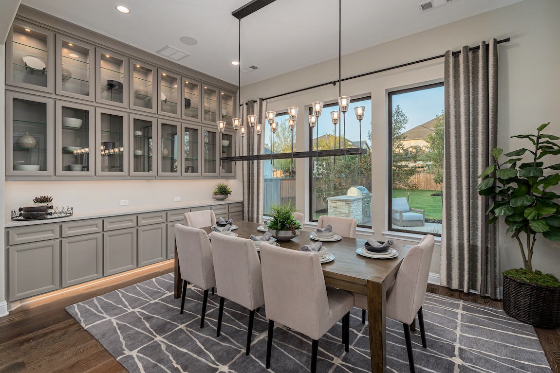 Casual dining room with a wood table, upholstered chairs, built-in cabinetry, and statement linear chandelier.