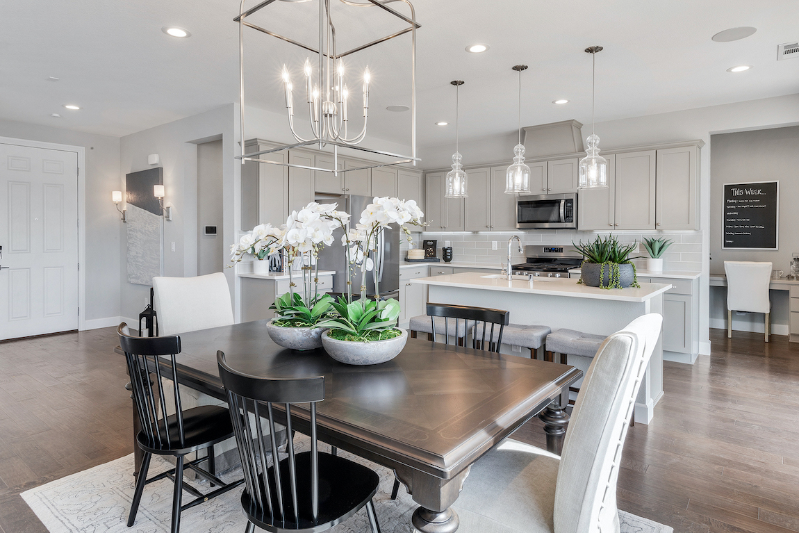 Brown wood nook table with white chairs in a white kitchen.