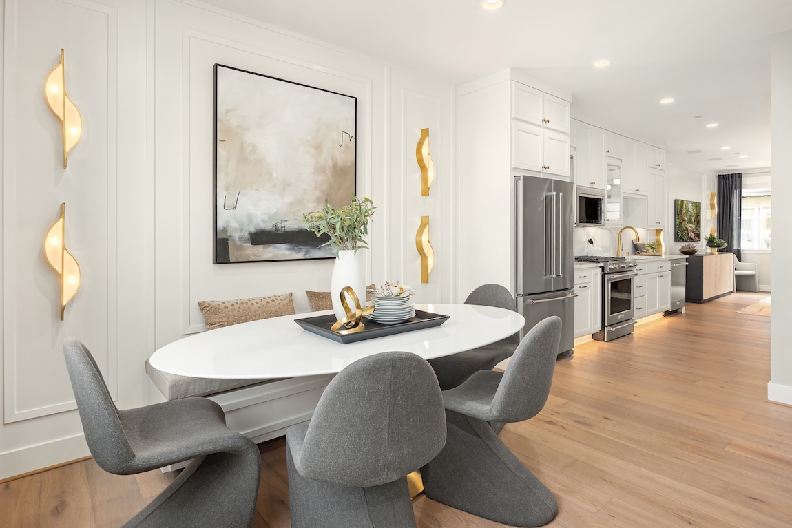 Modern casual dining nook with an oval table, gray upholstered chairs, built-in bench seating, and sculptural wall lighting.