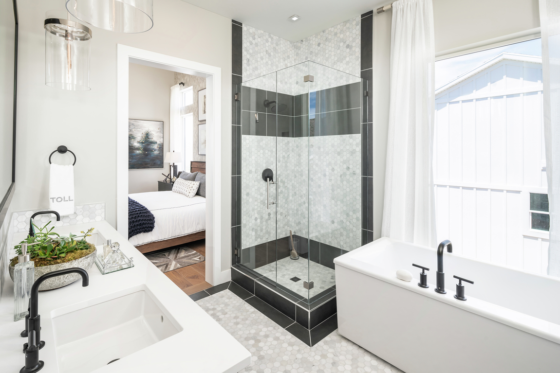Master bathroom with quartz and black tile and modern farmhouse sink with freestanding bath tub.