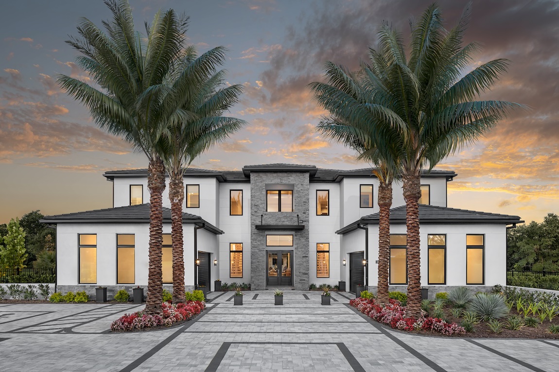 exterior of home with stone accents and palm tree lined driveway