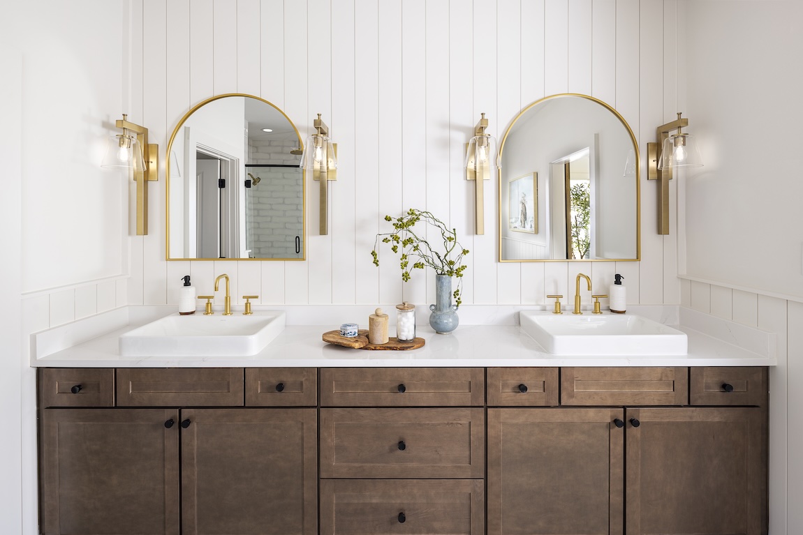 dual vanity sinks with gold fixtures and shiplap wall