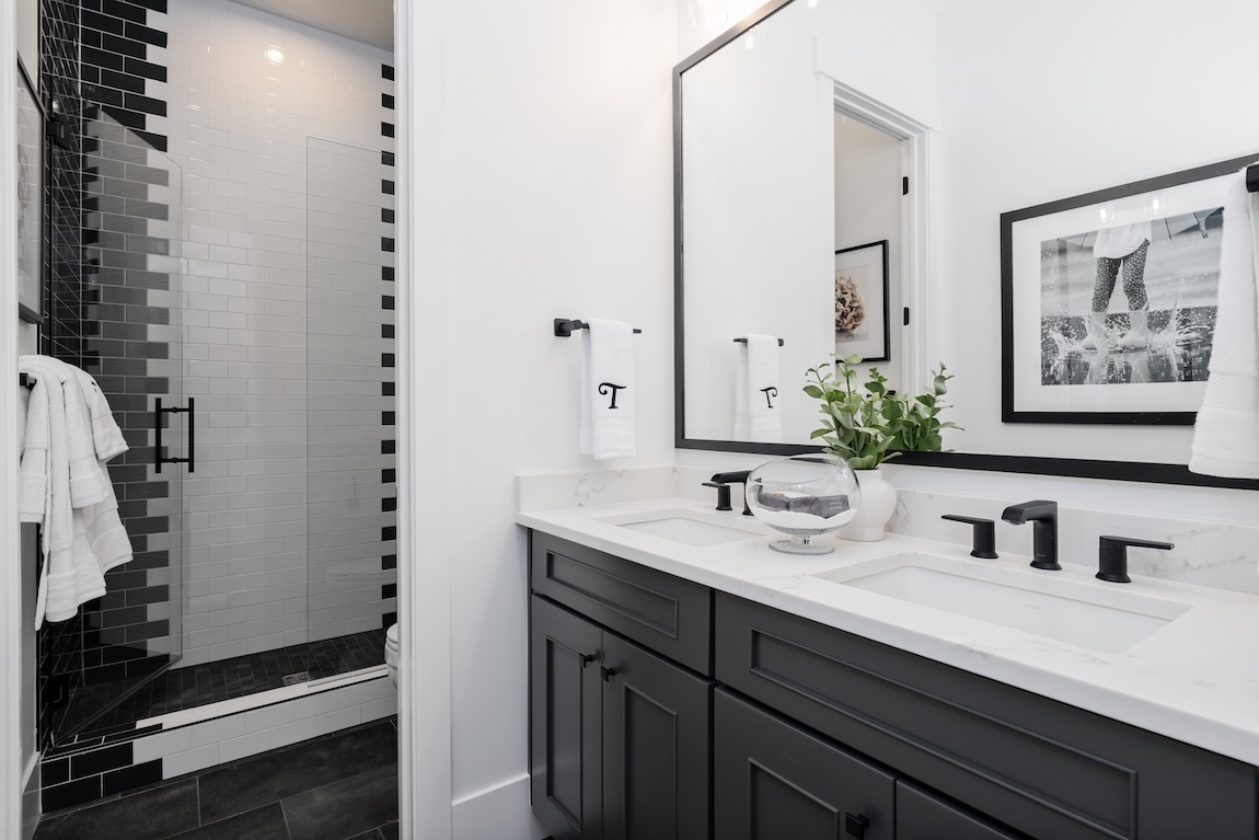 bathroom with dual sinks and dramatic black and white tiles