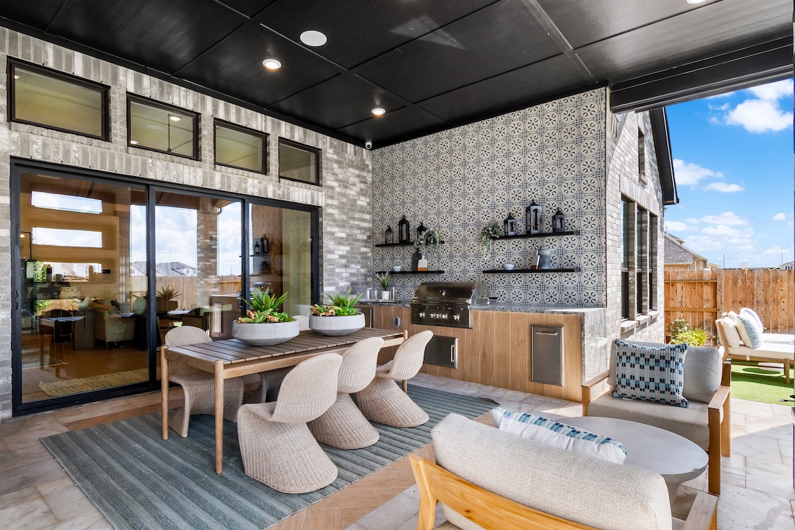 outdoor kitchen with dining table and tile walls