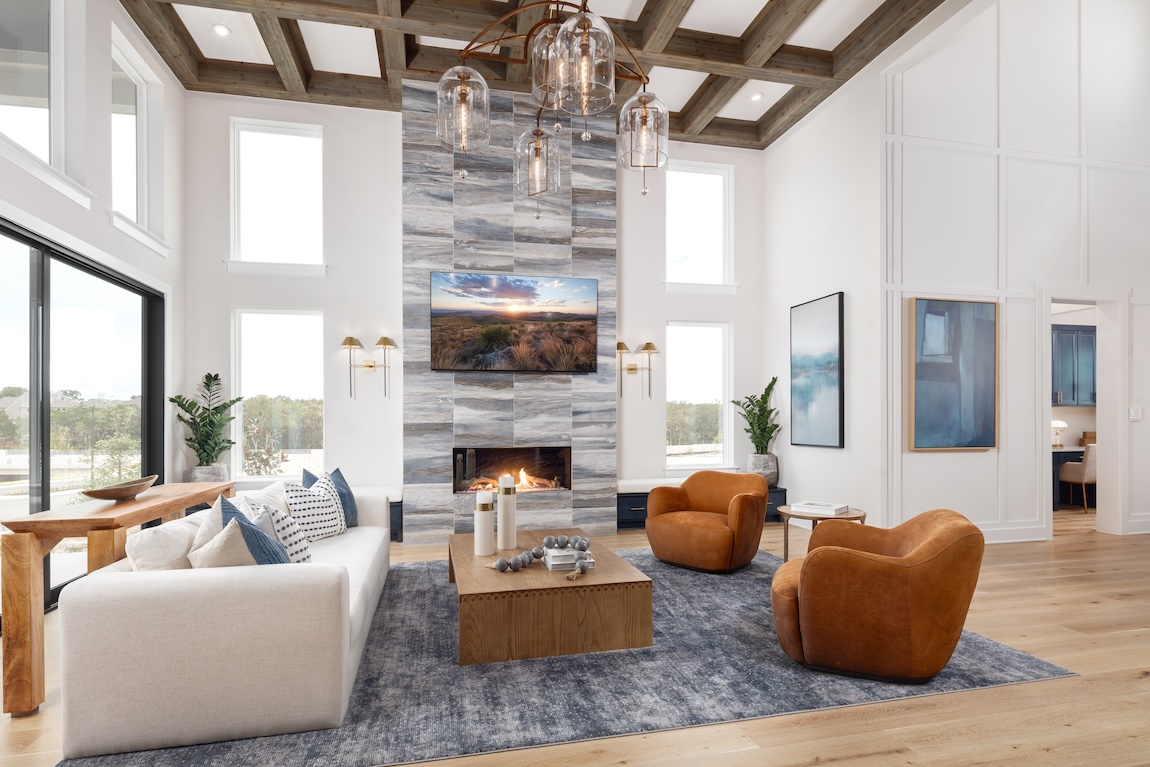 Fall interior design in a great room with warm leather chairs, natural wood, and a floor-to-ceiling fireplace