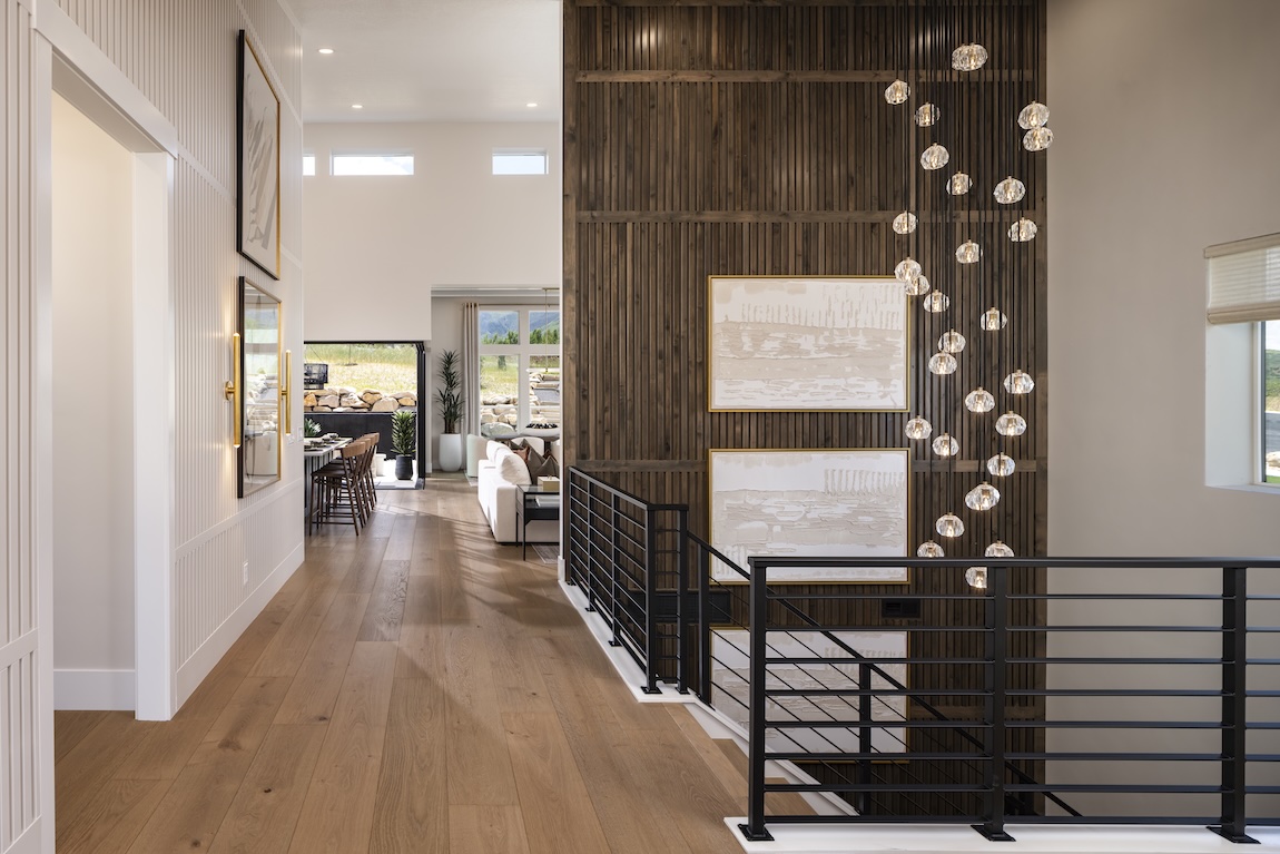 Modern entryway with rich wood accent walls, warm flooring, and cascading statement lighting