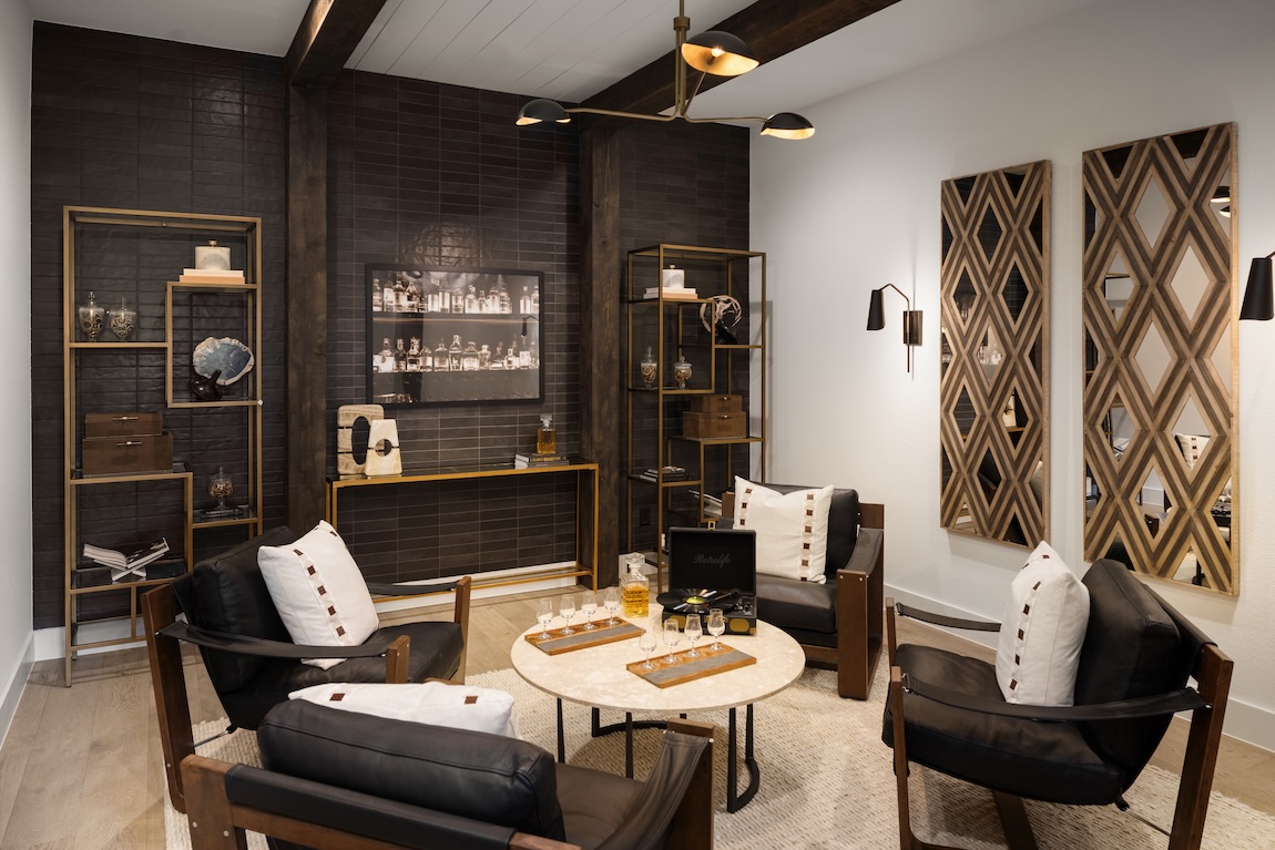 Moody lounge with dark wood, black tile, leather seating, and warm metallic accents