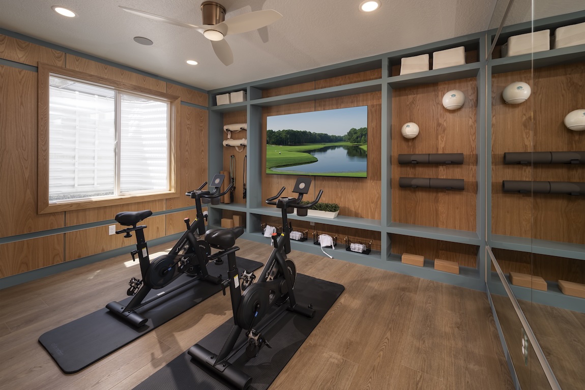 Home gym with warm wood paneling, built-in storage, and dedicated cycling equipment