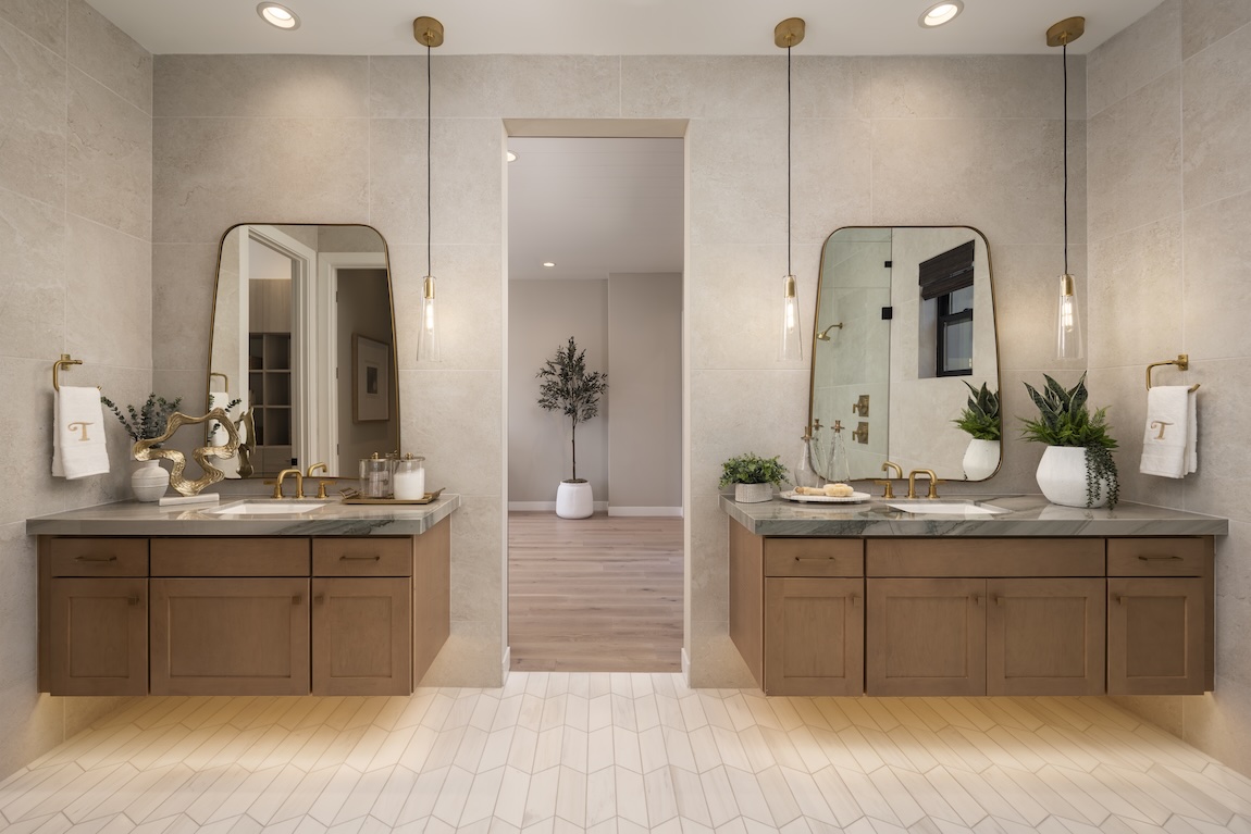 Spa-inspired bathroom with warm wood vanities, stone surfaces, and brass fixtures