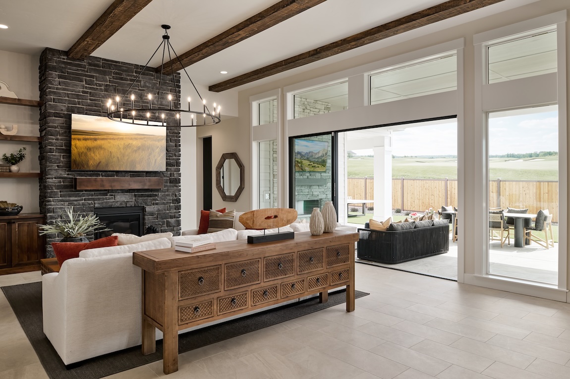 Fall interior design in a great room with rustic wood beams, stone fireplace, and warm earth-tone accents