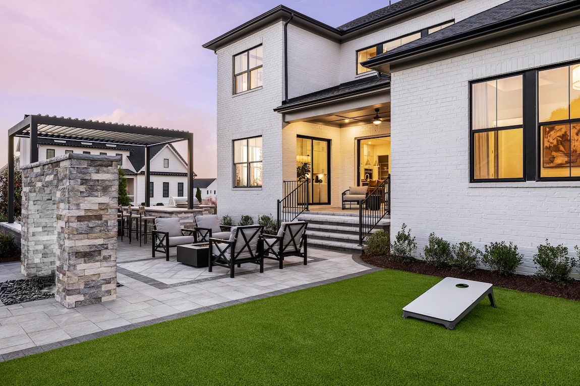 backyard space with cornhole and comfortable seating