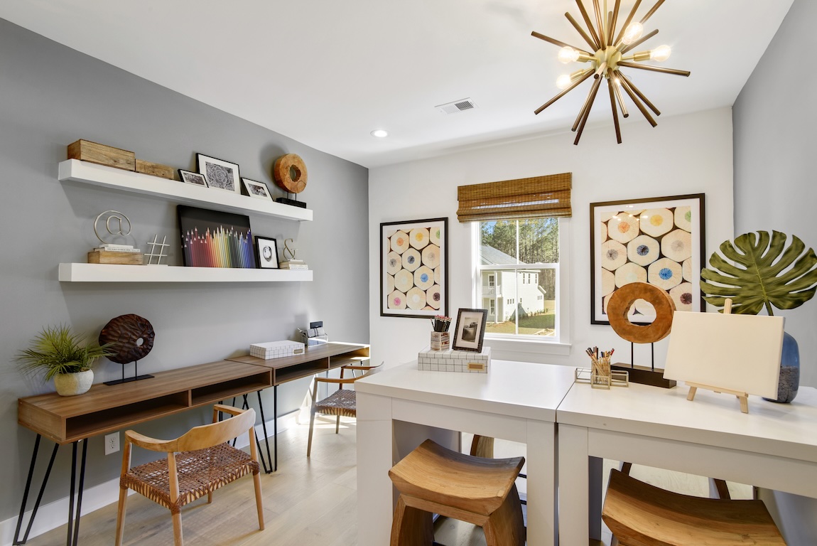 Creative craft room with spacious worktables, floating shelves, natural wood accents, and colorful artwork.
