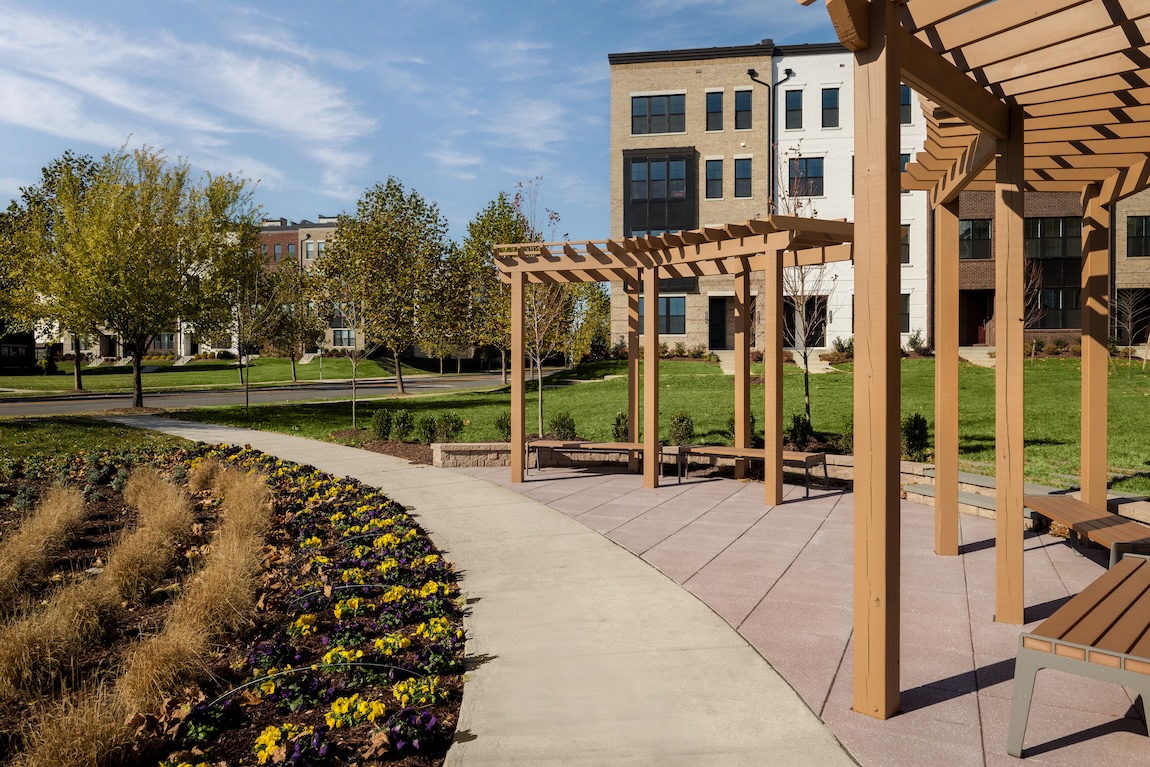 Landscaped community pocket park with pergolas, seating areas, walking paths, and colorful gardens.
