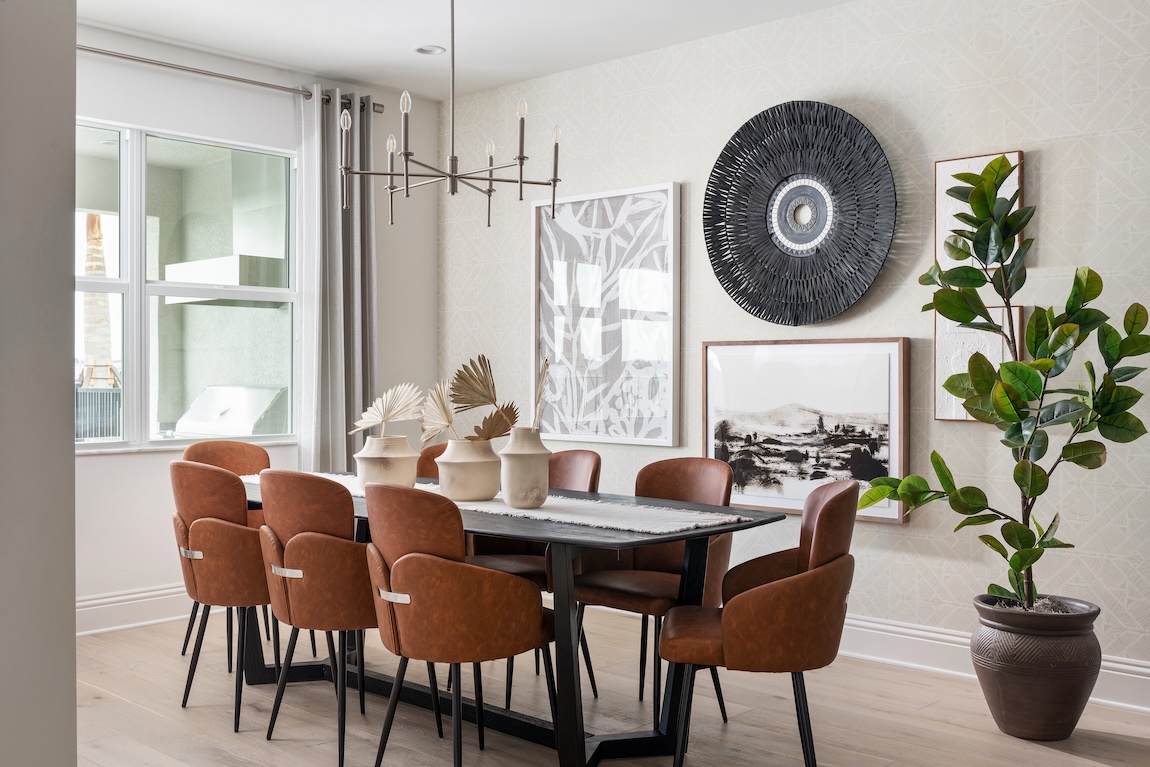 Contemporary dining room with leather chairs, statement wall art, modern chandelier, and potted greenery.