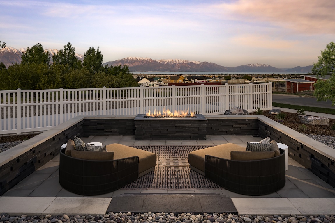 Outdoor fire pit lounge with built-in seating and panoramic mountain views at sunset.
