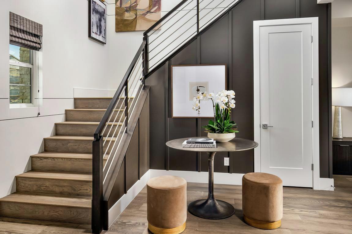 Cozy modern staircase with black metal railing and wood treads in a bright foyer with wall art and neutral-toned decor