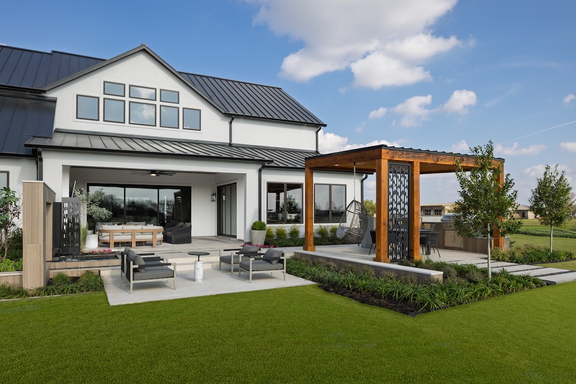 backyard of home with wooden pergola and grass space.