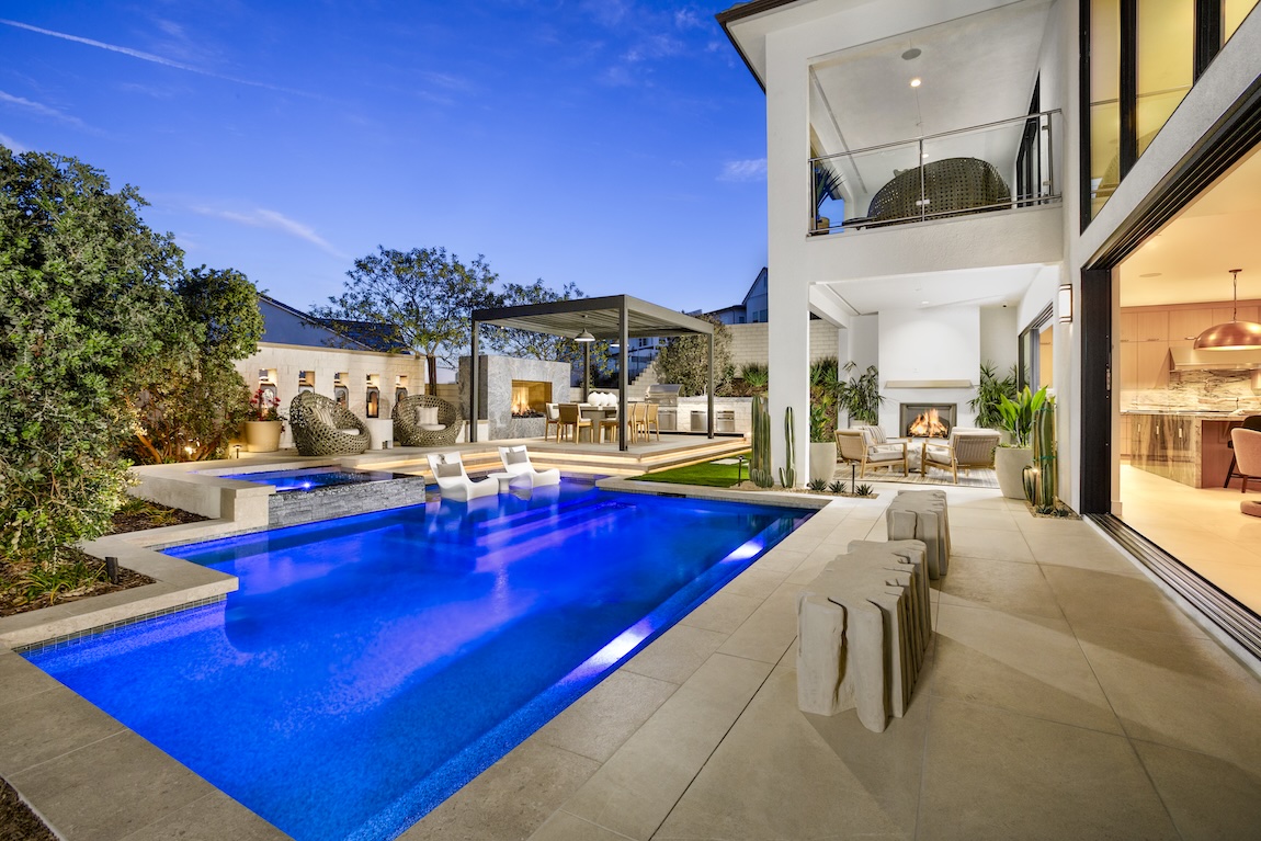 Luxury backyard oasis with pool, outdoor dining, and multiple fireplace lounge areas.