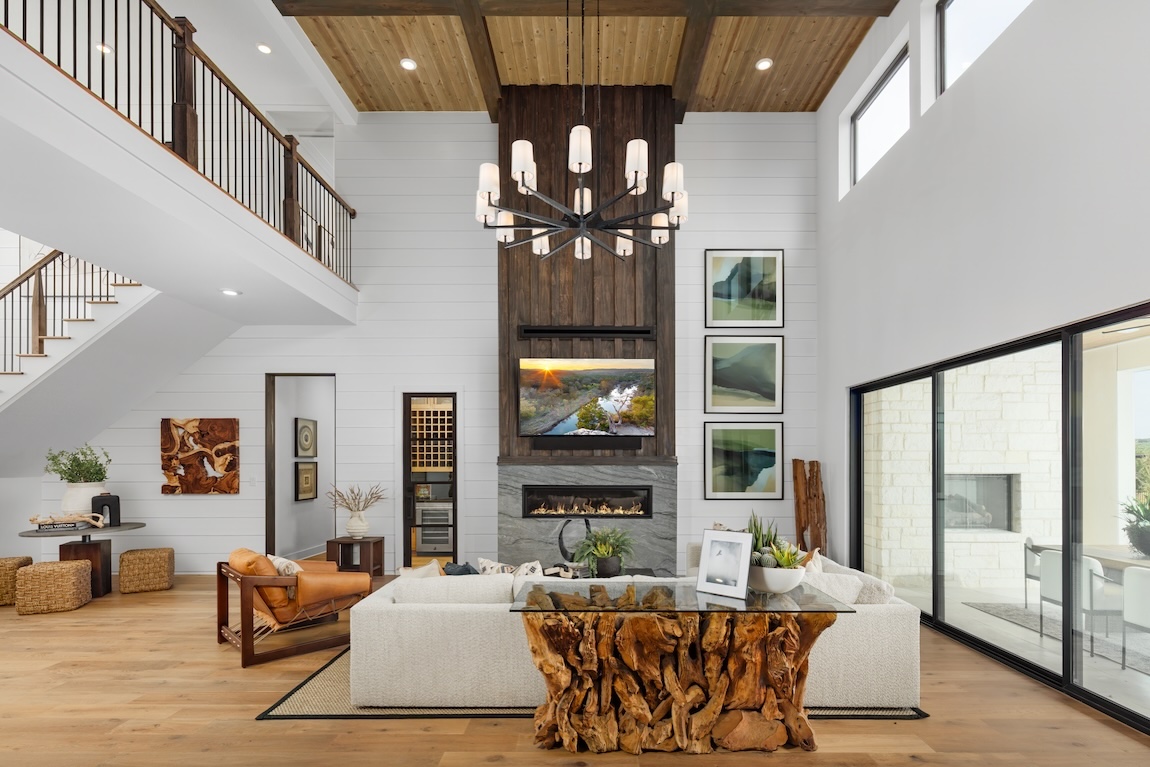 Expansive great room featuring a floor-to-ceiling fireplace with wood accents and modern styling.