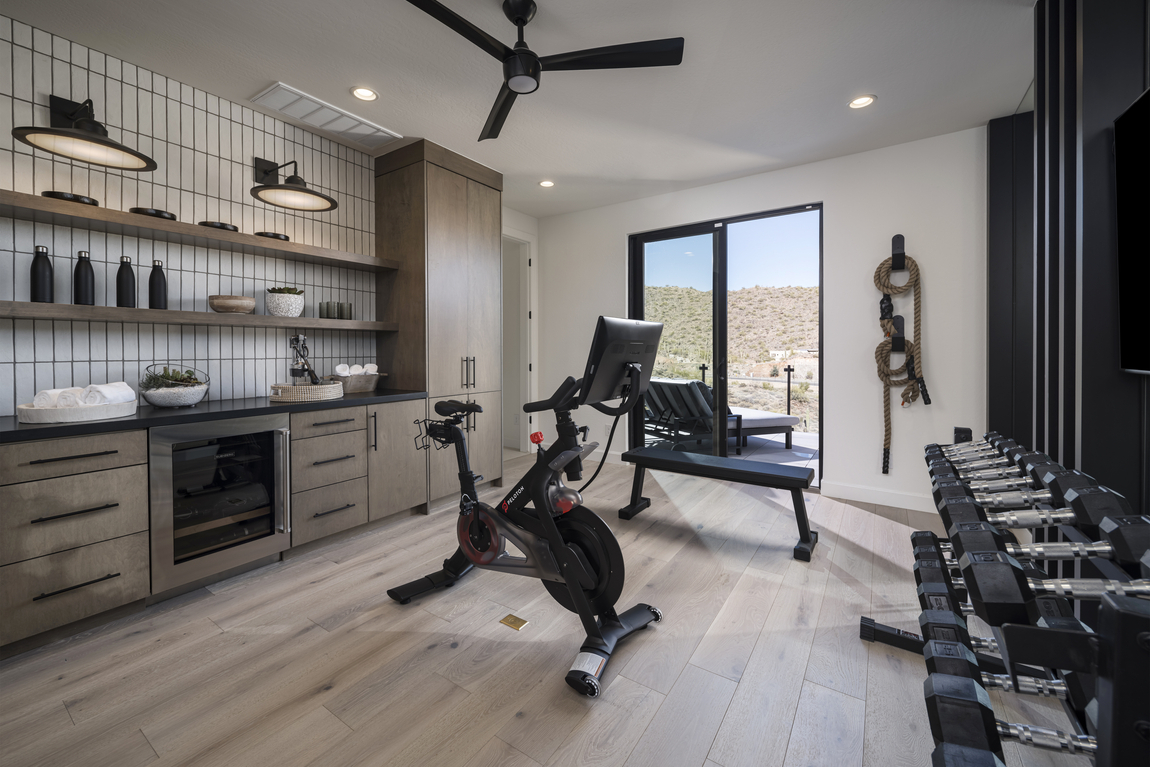 At-home gym featuring wet bar, mini fridge and workout equipment.