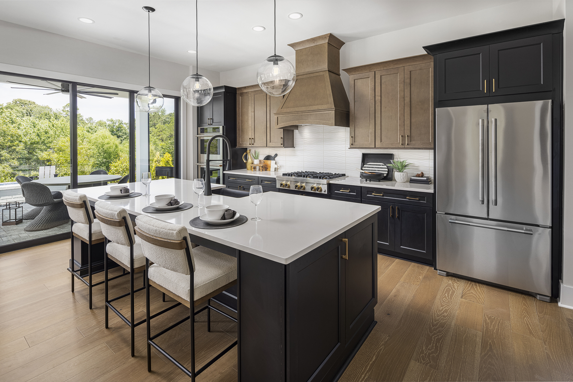 Luxury kitchen design with two-toned brown and black cabinets, black island and quarter countertop.