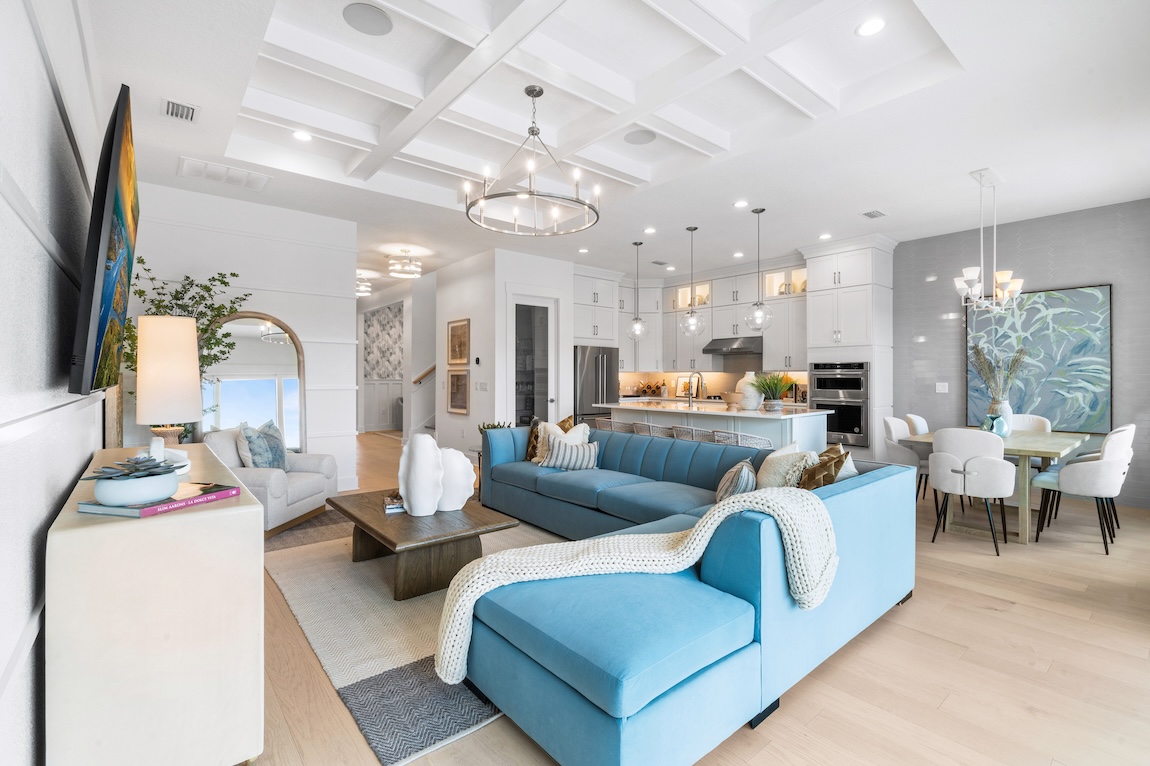 Luxury living room with light blue couch and white kitchen with beige flooring.