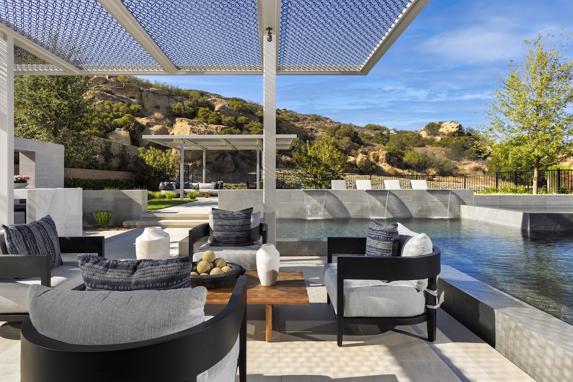 outdoor lounge space with pergola overhead, next to the pool
