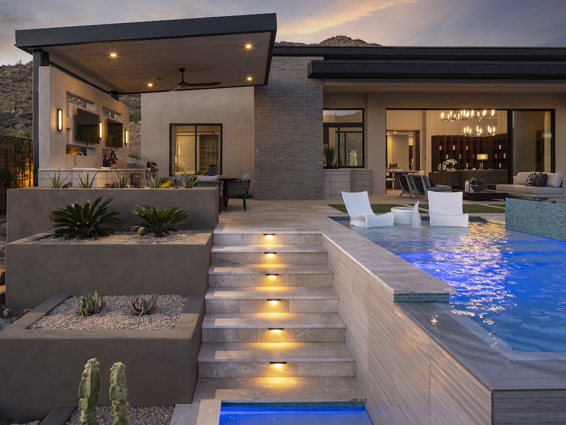 Innovative hardscape design highlighted by lighting next to pool