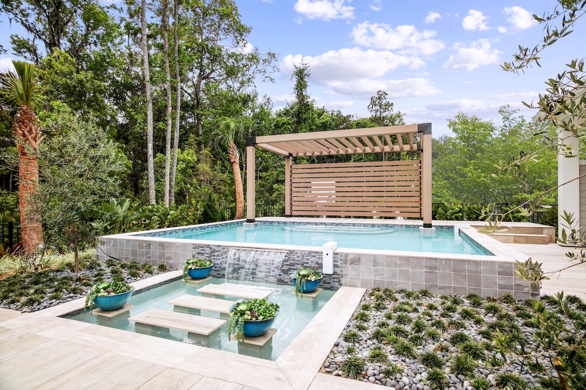 Impressive backyard that blends greenery, natural textures and colors, and a modern pool design to create a tropical oasis