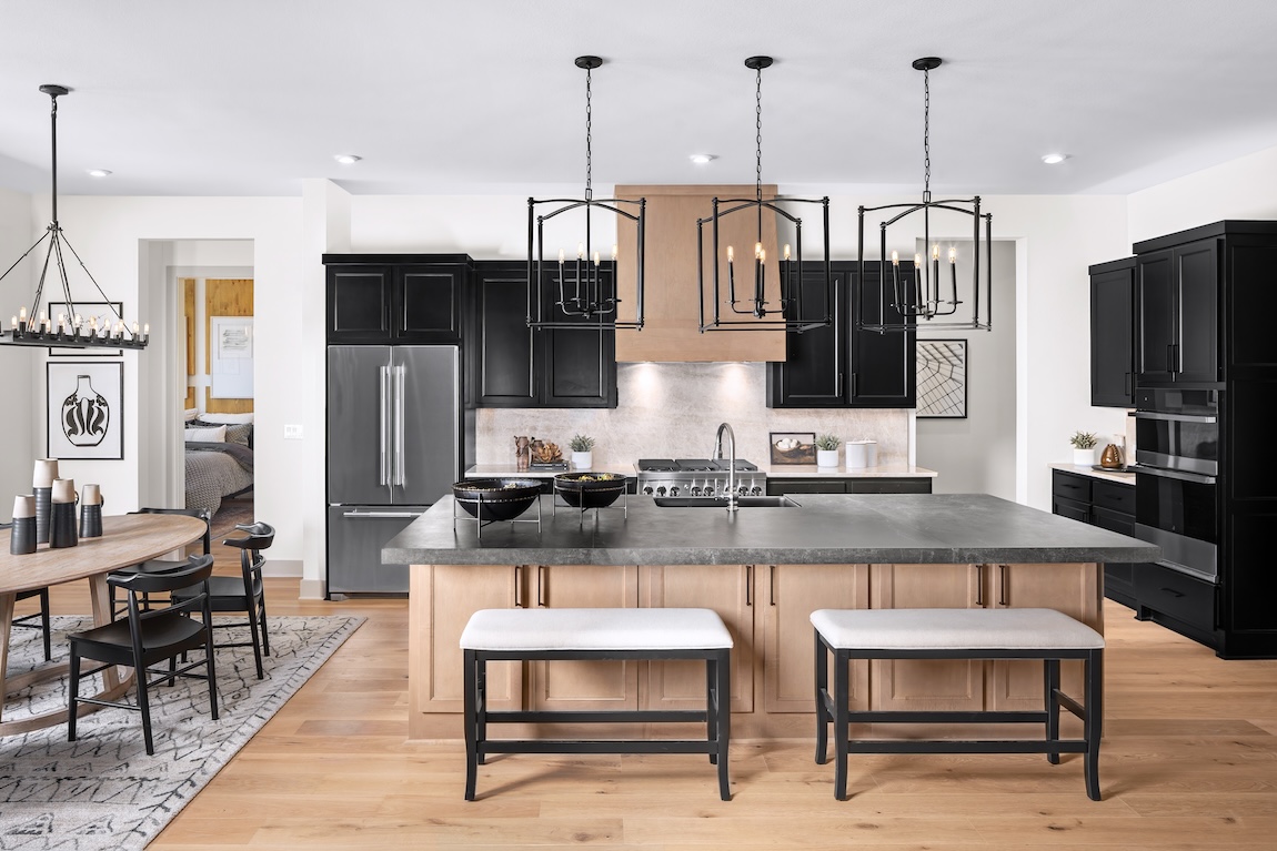 Luxury kitchen design with pendant lighting, an island with a gray quartz countertop, and metal bench stools. 