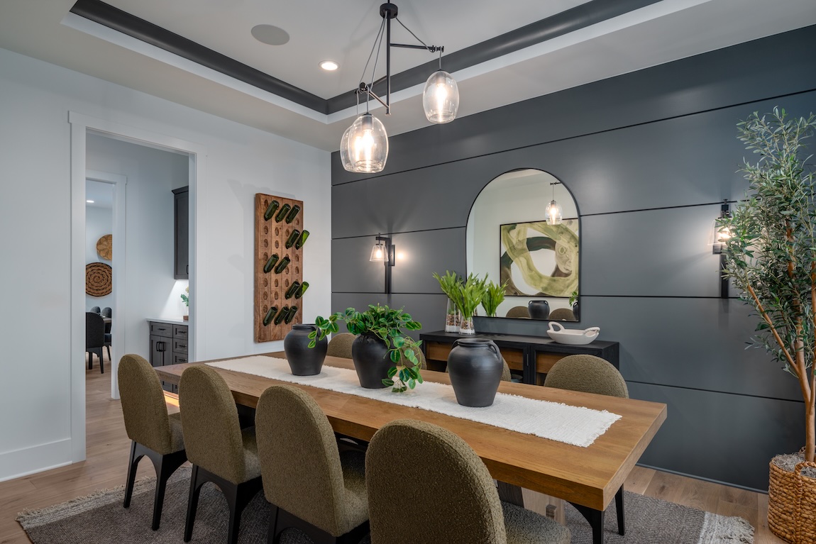 Dramatic dining room with rain cloud paneled feature wall from the Sherwin-Williams 2025 color capsule, modern wood table, olive green chairs, and soft lighting for a luxe, moody ambiance.