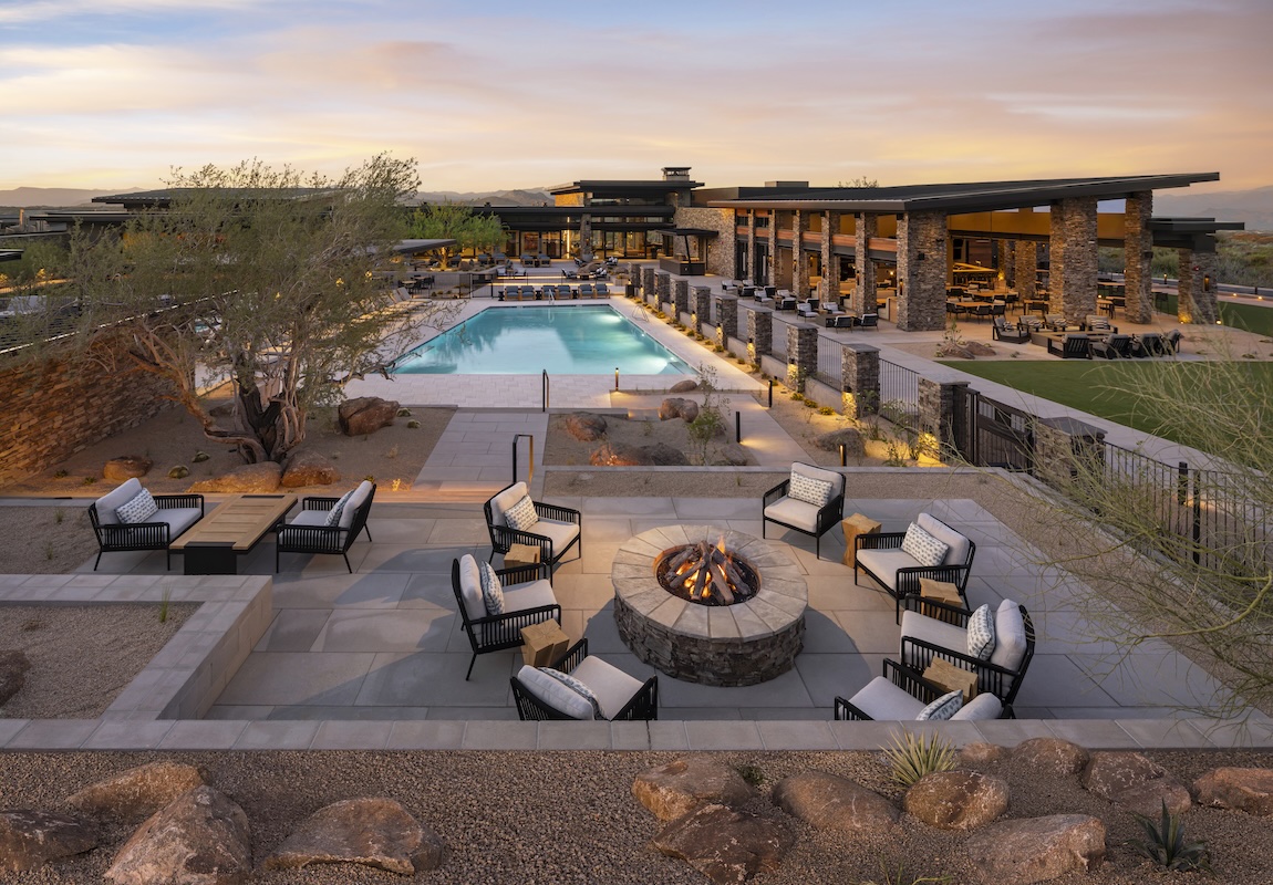Luxury desert resort at sunset featuring a modern outdoor lounge with a central fire pit, poolside seating, and expansive patio architecture surrounded by desert landscaping. Winner at Gold Nugget Awards